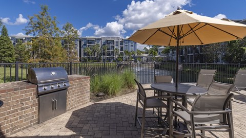 a patio with a grill and a table with chairs and an umbrella