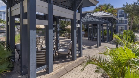 a covered patio with tables and chairs and a building in the background