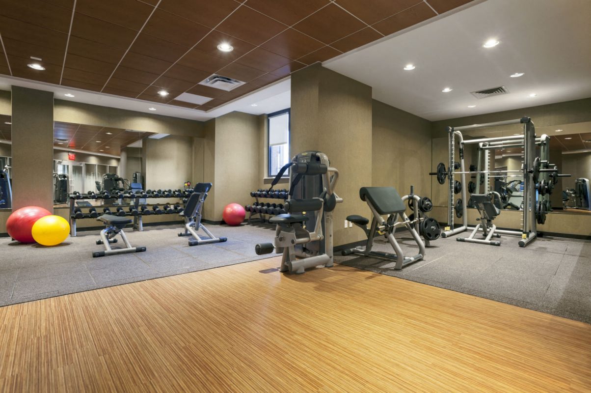 a gym with weights and balls on a wooden floor