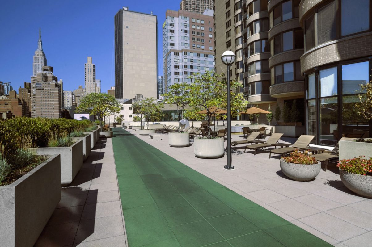 a view of a sidewalk with benches and buildings in the background