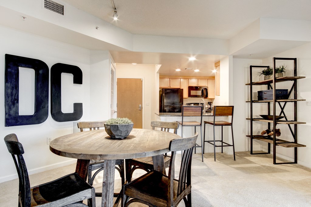 a dining area with a table and chairs and a kitchen in the background