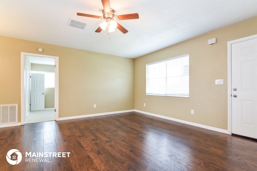 an empty living room with wood floors and a ceiling fan