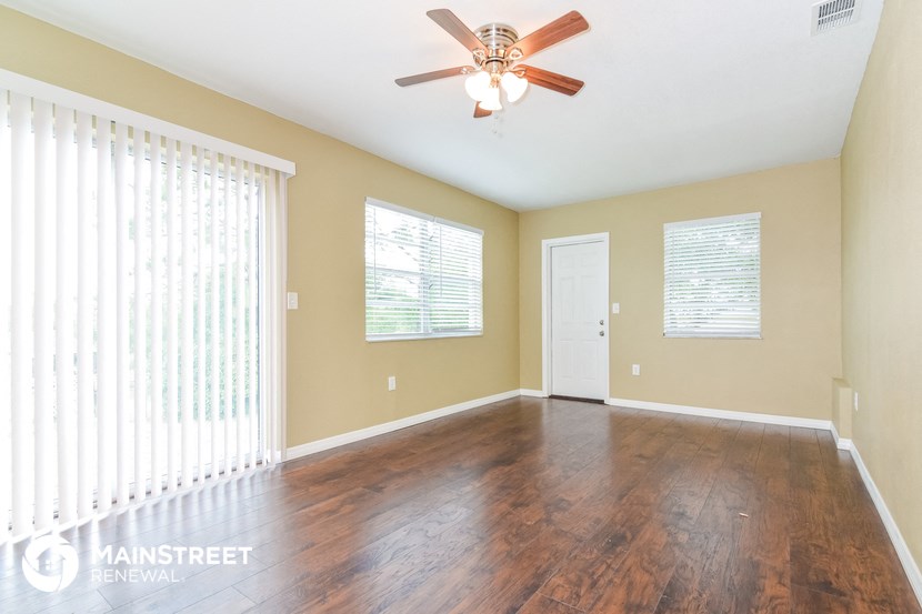 an empty living room with wood floors and a ceiling fan