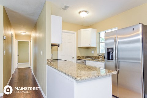 a kitchen with a marble counter top and a stainless steel refrigerator