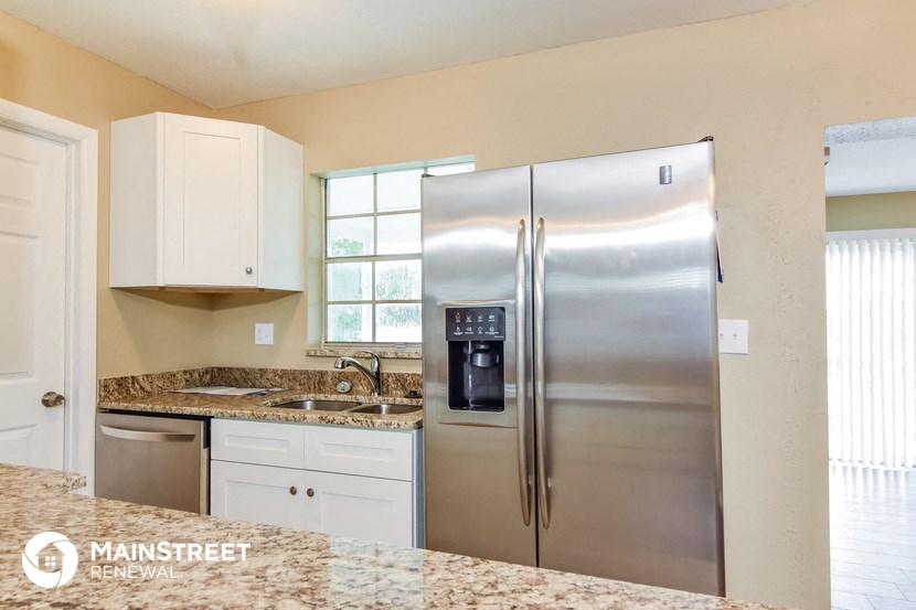 a kitchen with a stainless steel refrigerator and white cabinets