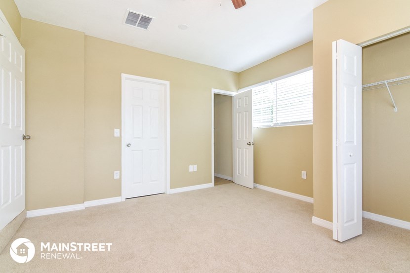a bedroom with two closets and two doors and a carpeted floor
