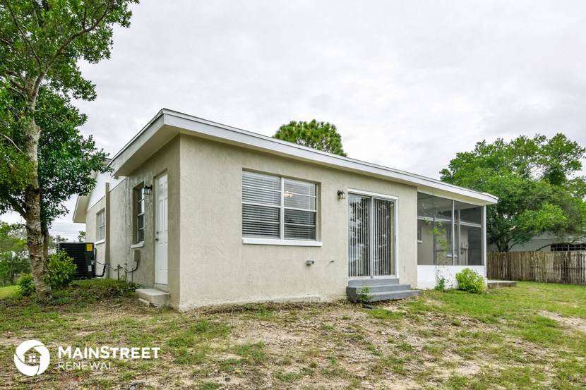 the exterior of a small white house with grass and trees