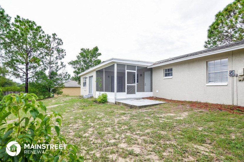 a small white house with a yard and a backdoor