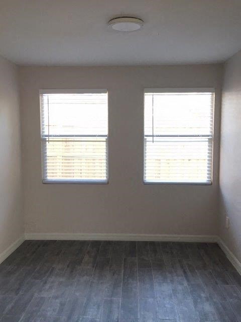 an empty room with two windows and a wood floor