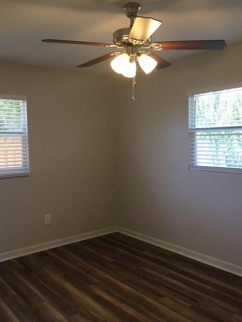 a living room with a ceiling fan and two windows