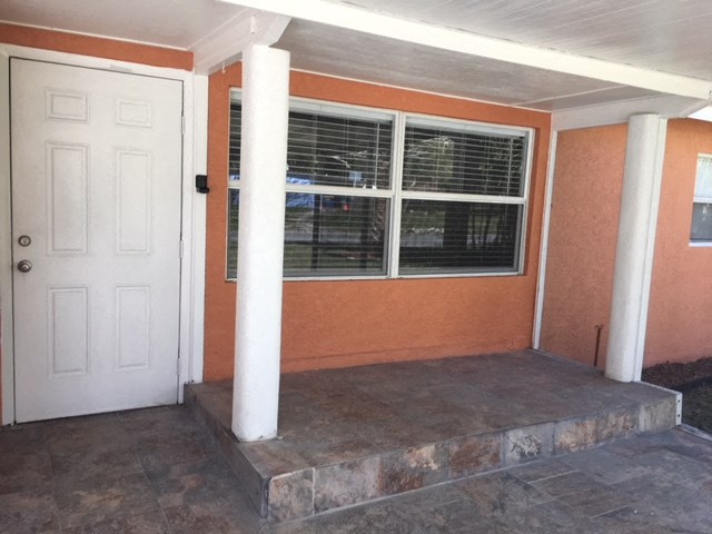 an empty porch of a house with a white door