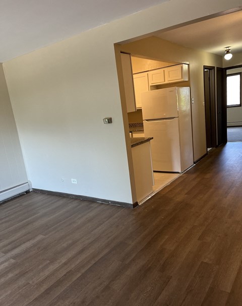 A kitchen with a white fridge and wooden floors.