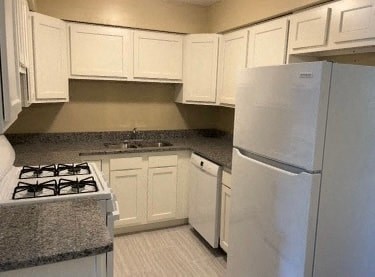 A kitchen with white cabinets and a white refrigerator.