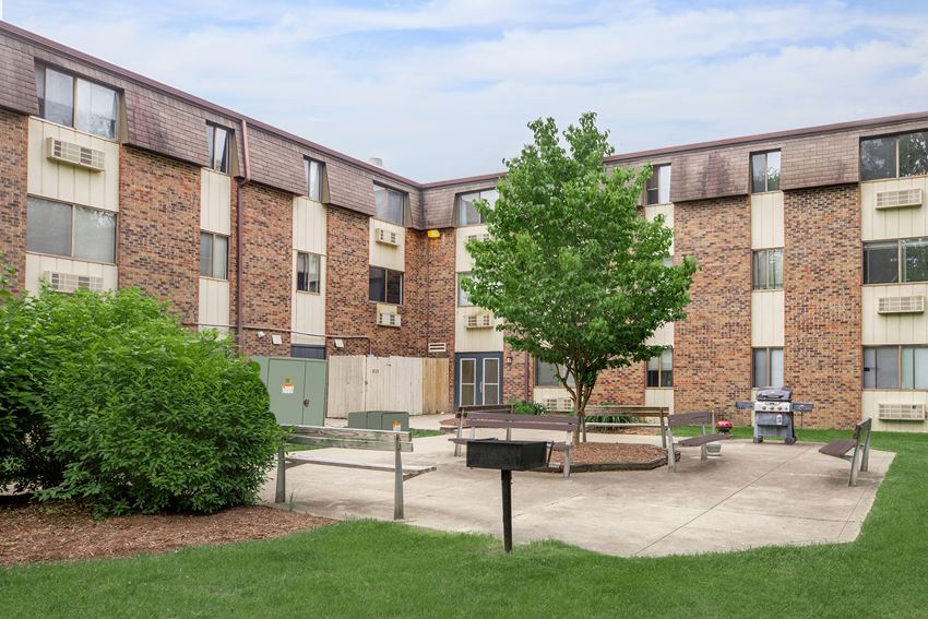 a courtyard with a tree in front of a brick building