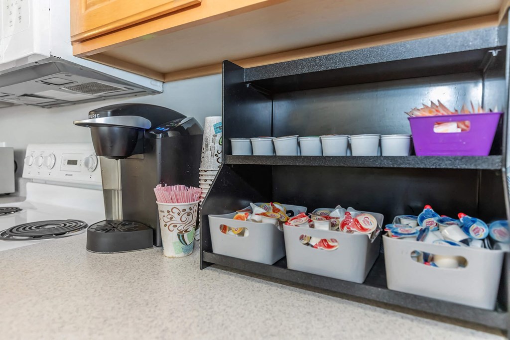 a kitchen counter with coffee cups and a coffee maker