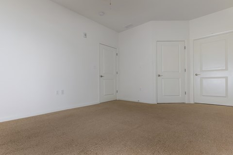 a bedroom with white walls and carpet and two doors