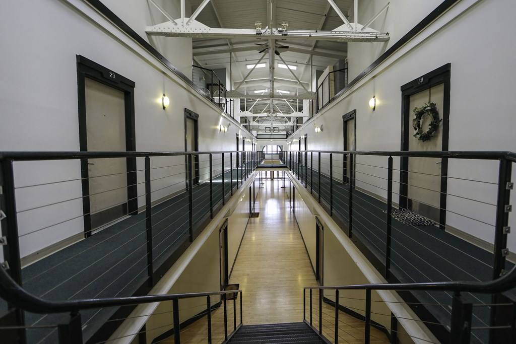 a hallway with railings and doors in a building with a ceiling