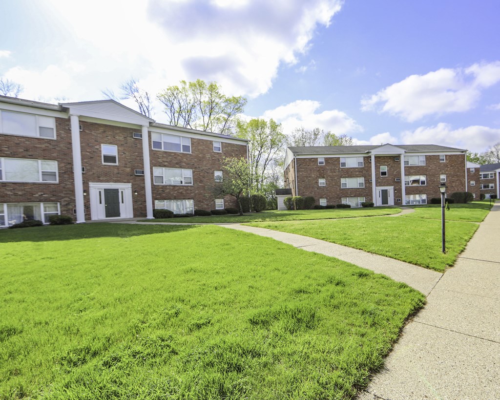 an exterior view of an apartment building with a lawn and sidewalk