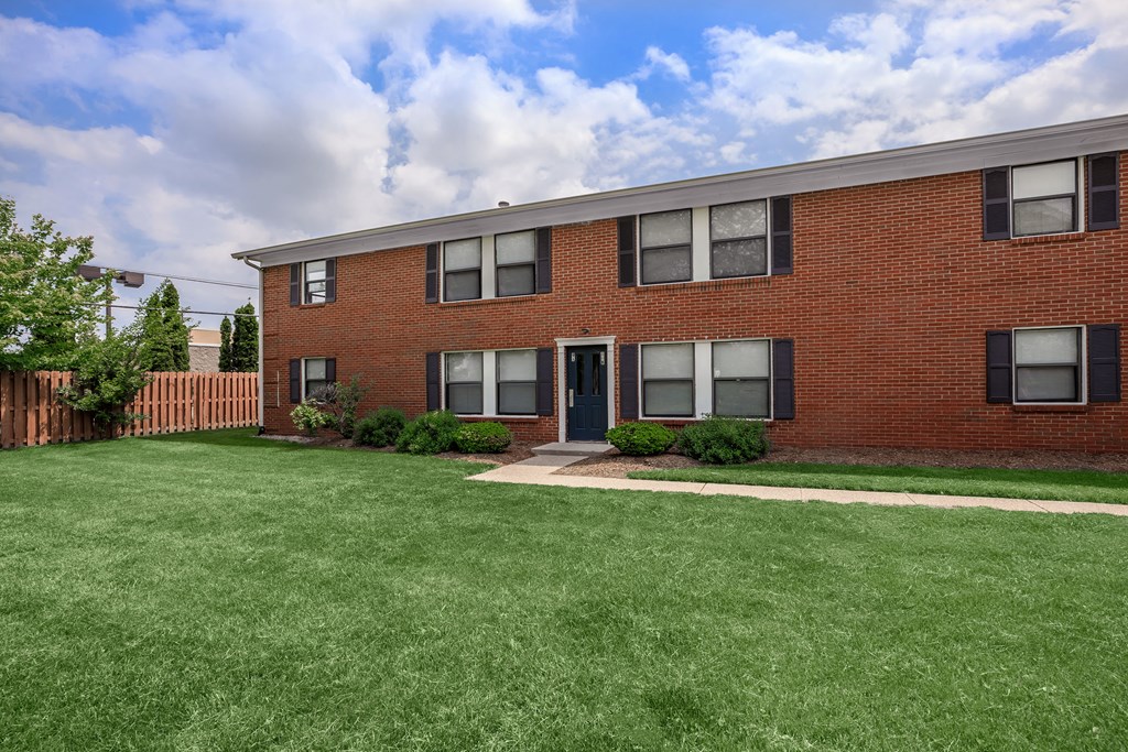 a brick apartment building with a lawn in front of it