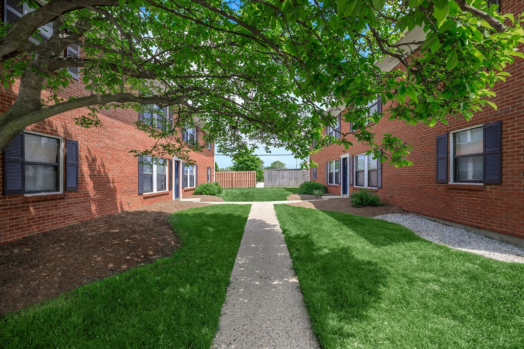 a walkway between two brick buildings with grass and trees
