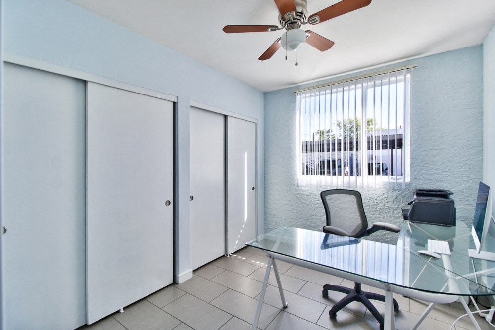 a office with a glass desk and a ceiling fan
