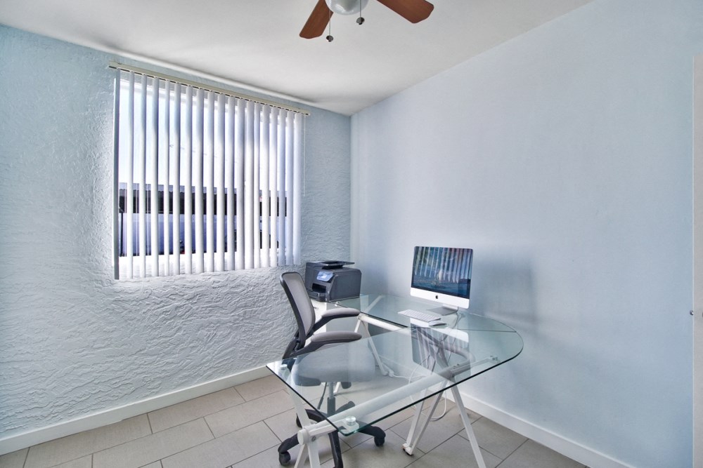 a home office with a glass desk and a computer