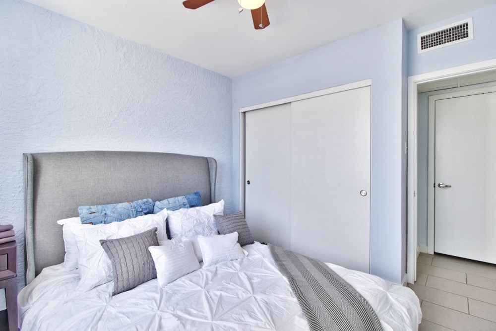 a bedroom with a bed and a closet and a ceiling fan