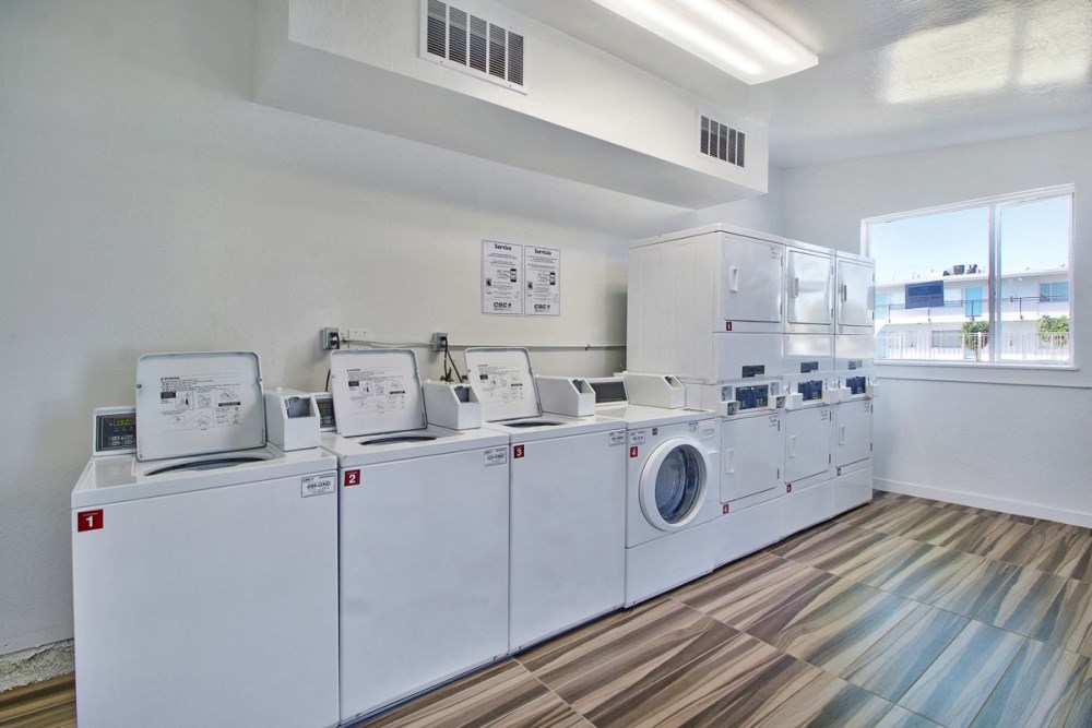 a group of washers and dryers in a room with a window
