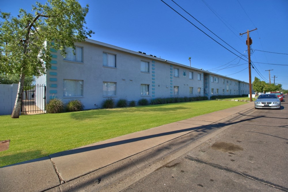 a long white building with a lawn and a car parked in front
