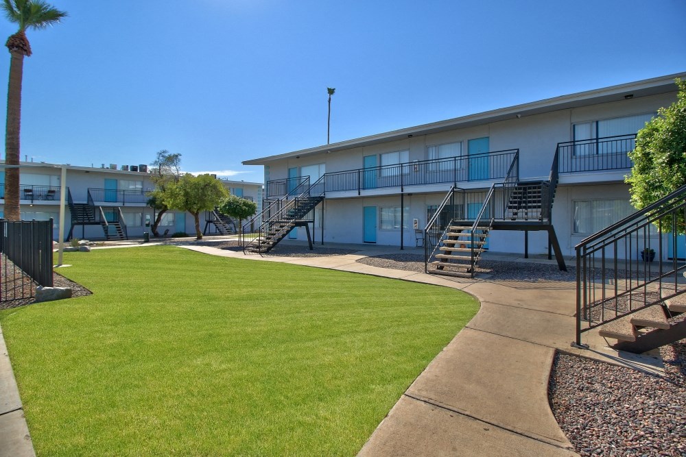 an apartment building with stairs and a grass yard