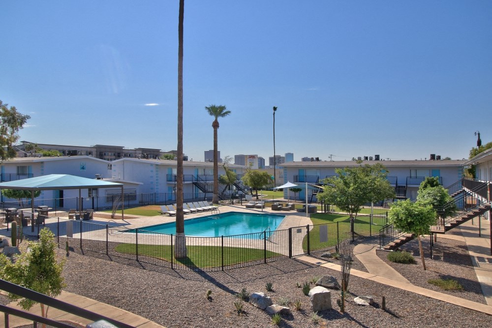 a resort style swimming pool with trees and buildings in the background