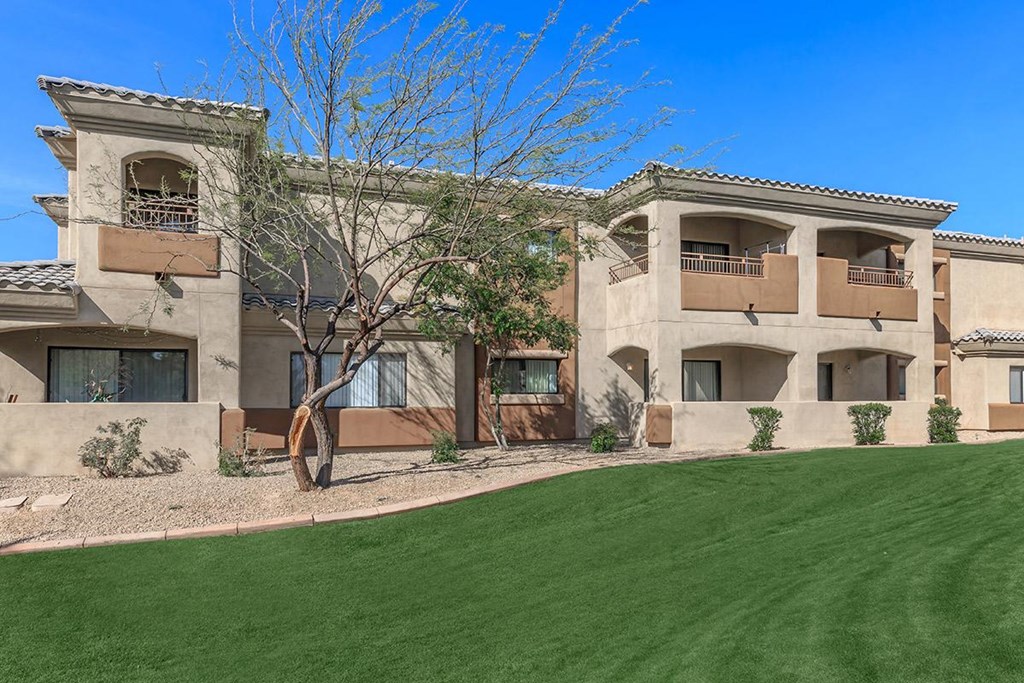 an apartment building with a green lawn in front of it