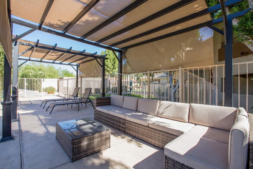 a patio with a couch and tables under a roof