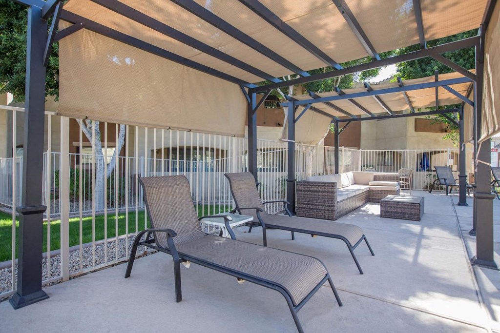 a covered patio with two chairs and a couch