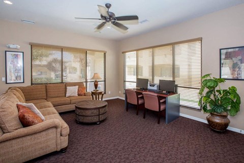 a living room with a couch and a desk and a ceiling fan