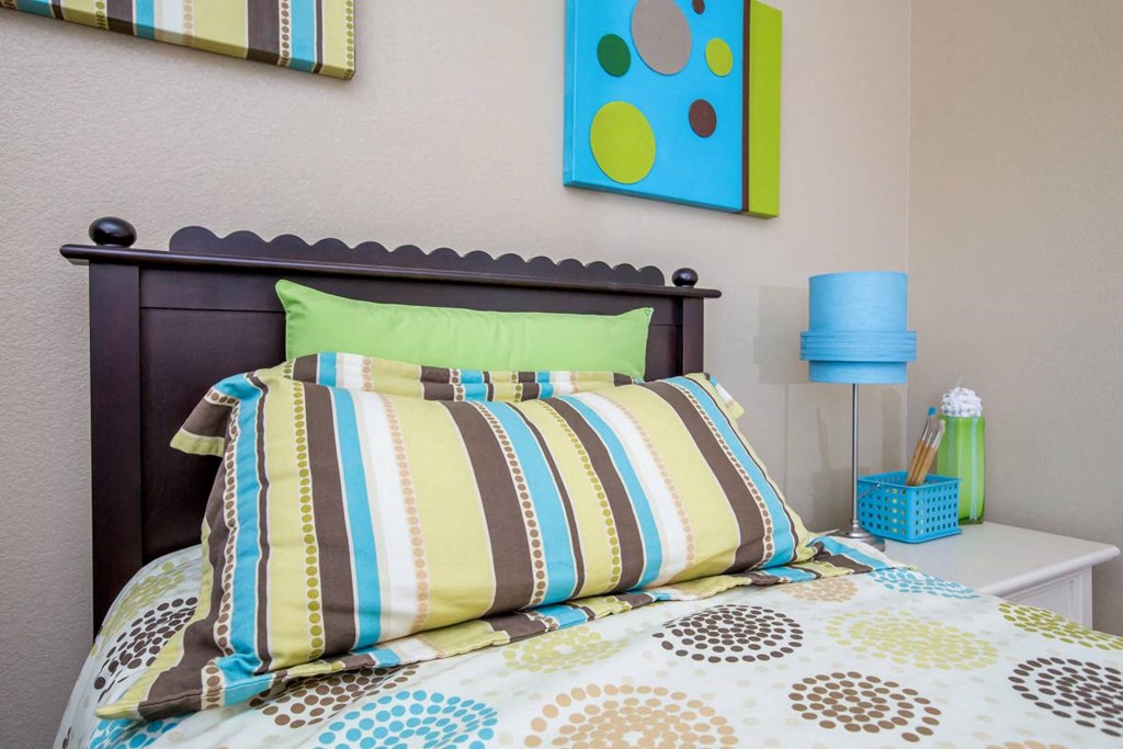 a bed with colorful pillows in a small bedroom