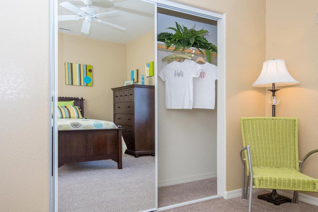 a bedroom with a closet and a chair and a dresser