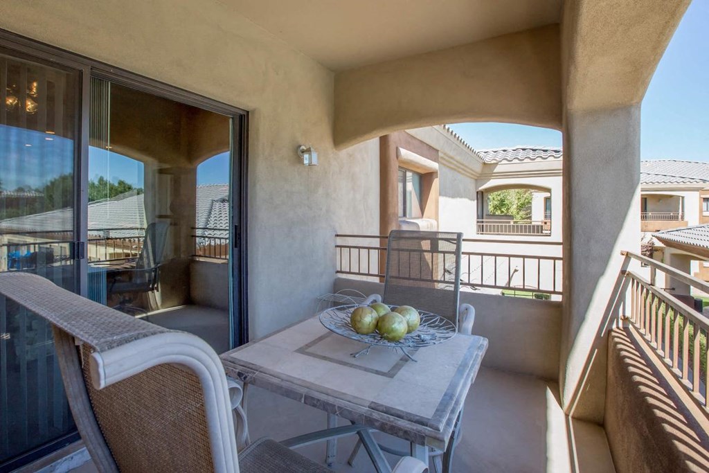 a patio with a table and chairs and a bowl of fruit on it
