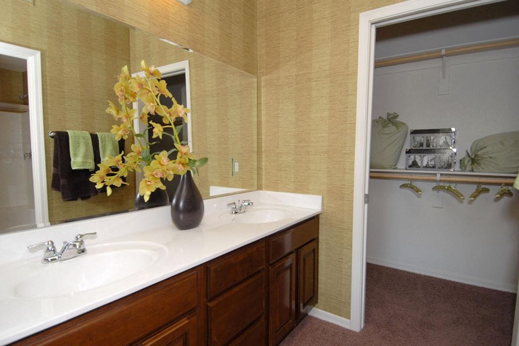 a bathroom with two sinks and a vase with yellow flowers