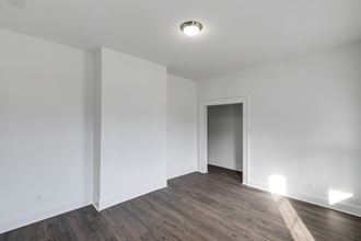 an empty living room with white walls and wood flooring