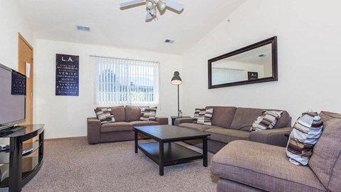 A living room with a couch, a coffee table, and a flat screen TV.