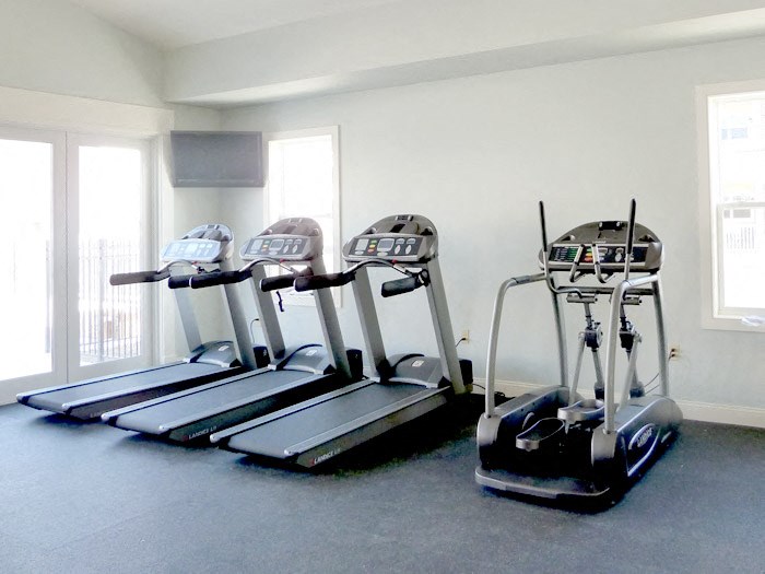 three treadmills in a gym room with windows