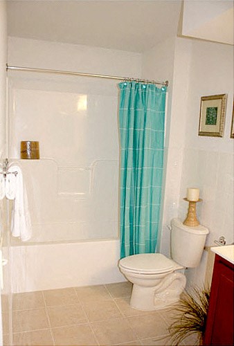 a white bathroom with a white toilet and a blue shower curtain