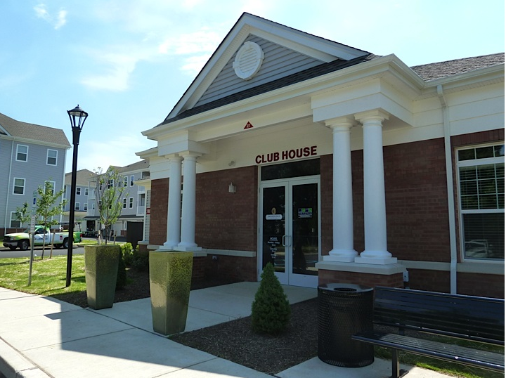 a club house with white columns and a bench in front of it