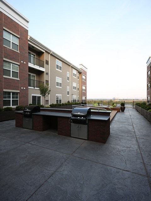 a patio with two bbq pits in front of an apartment building