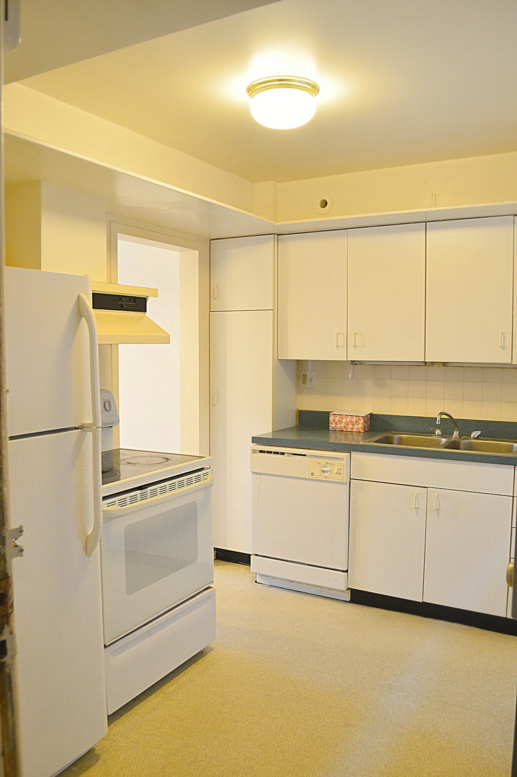 an empty kitchen with white appliances and white cabinets