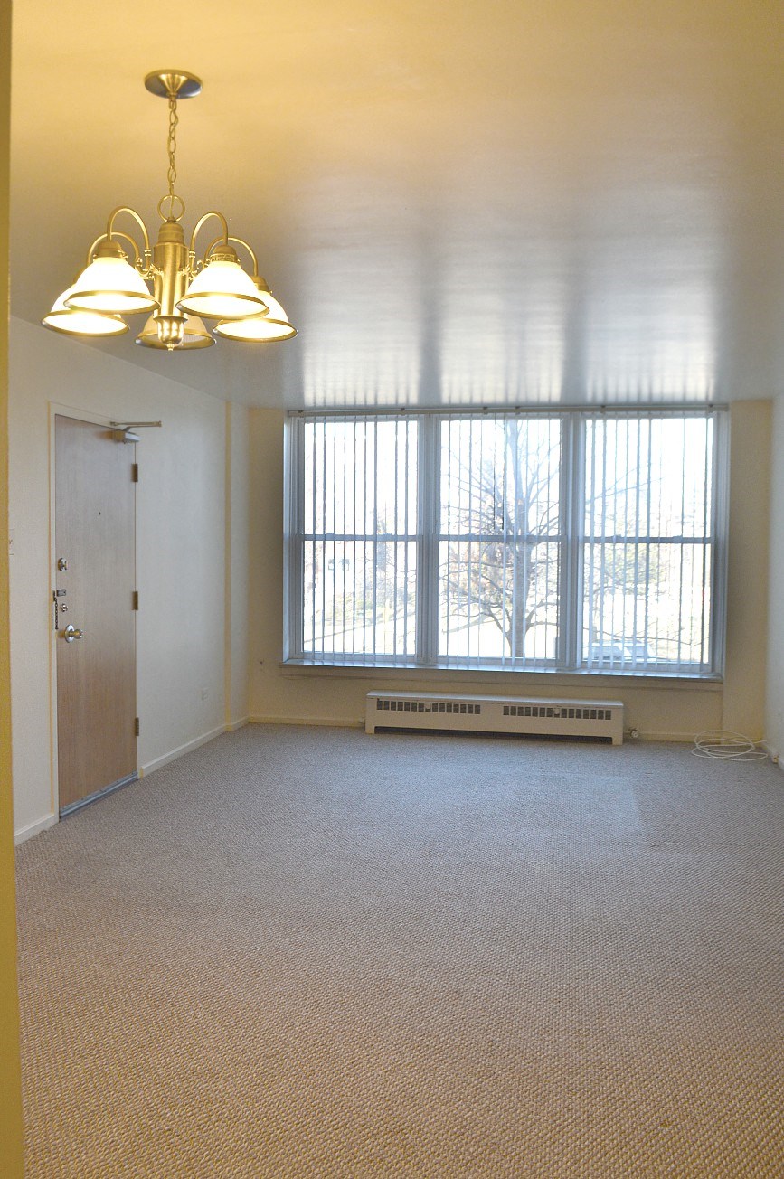an empty living room with large windows and a chandelier