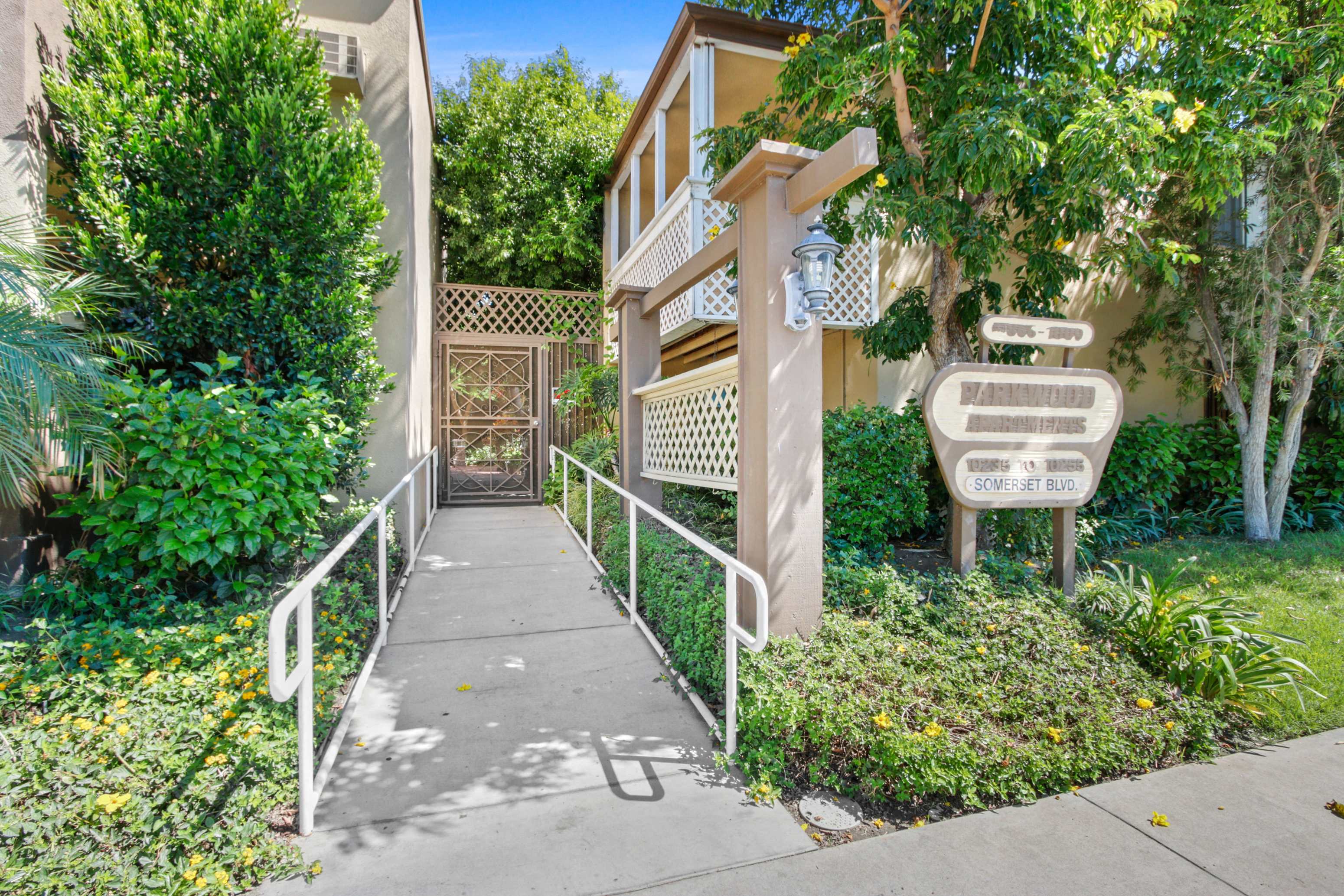 a sidewalk in front of a building with a staircase and a gate