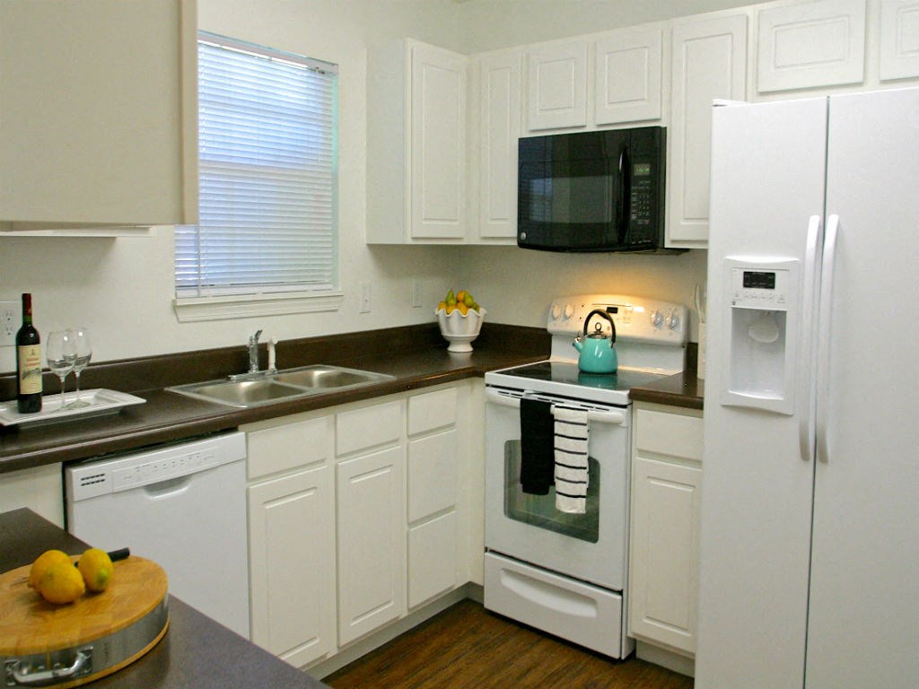 a kitchen with white cabinets and a black counter top