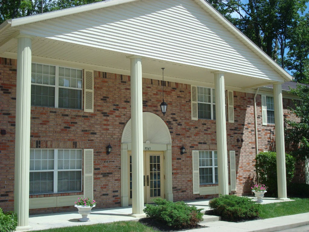 the front porch of a brick house with columns